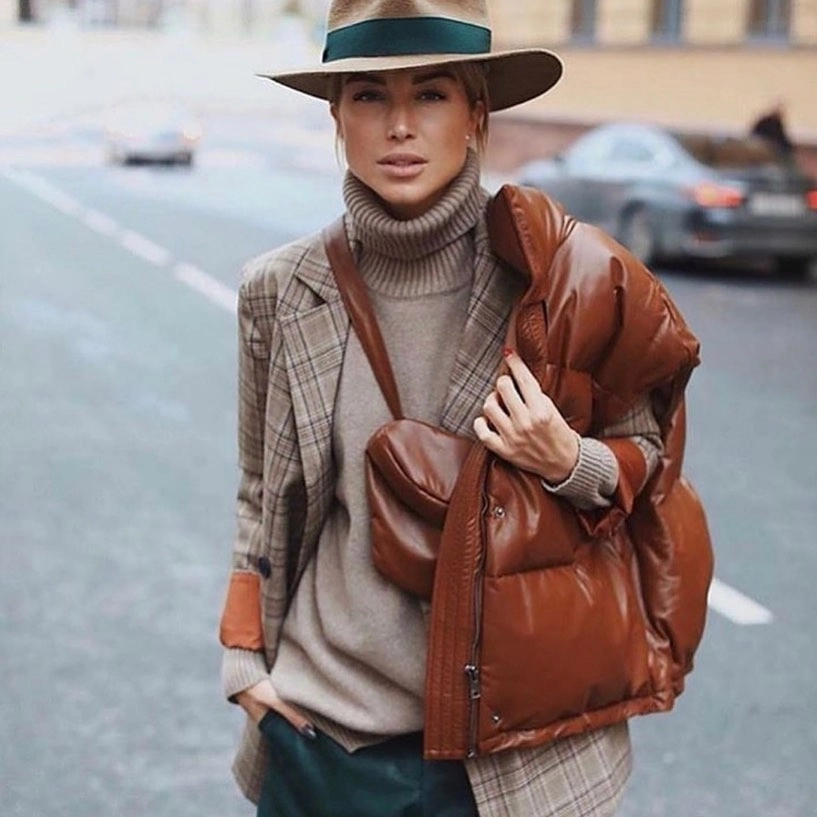 Woman wearing a beige turtleneck, plaid blazer, and brown padded jacket